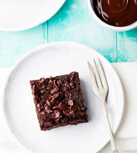 Chocolate brownie, cake on a white plate on a turquoise wooden background