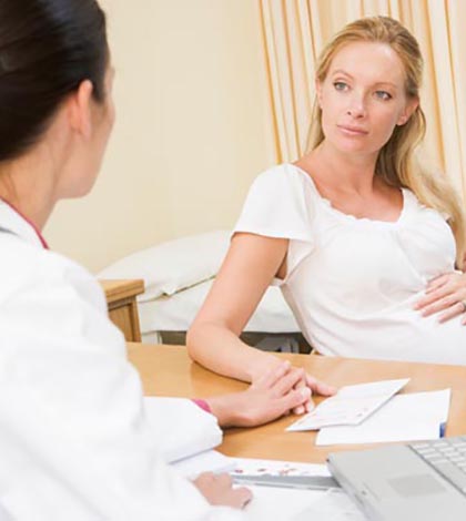 Doctor with laptop and pregnant woman in doctor's office