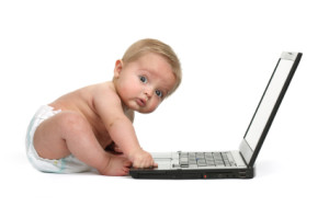 Surprised expression on a baby boys face whilst getting into mischief on a laptop computer