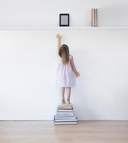 Young girl reaching for electronic book reader